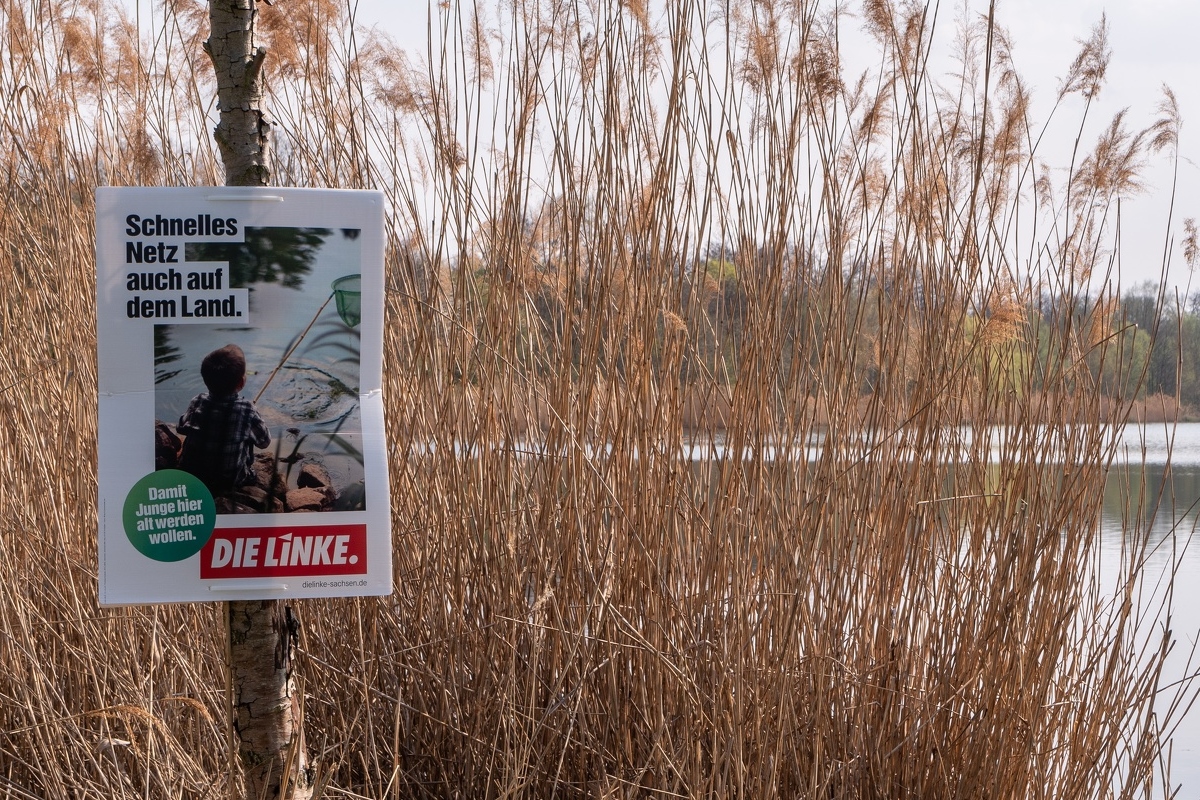 Zu sehen ist ein Wahlplakat mit dem Text: "Schnelles Netz auch auf dem Land." Auf dem Plakat sitzt ein Kind mit Fischnetz an einem See. Das Plakat selbst hängt auch an einem See.