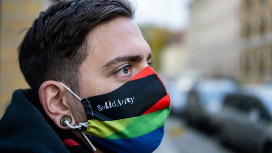 Junger Mann von der Seite mit einer bunten Maske mit dem Aufdruck "Solidarity"