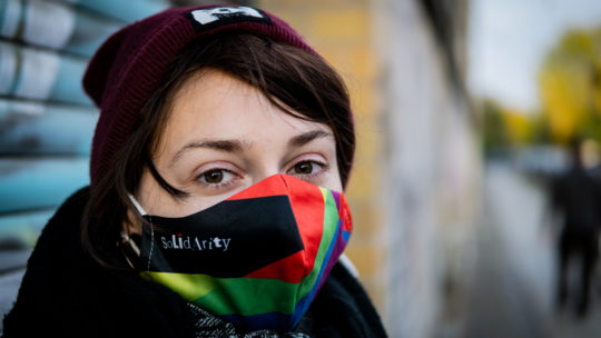Junge Frau mit einer bunten Maske mit dem Aufdruck "Solidarity"