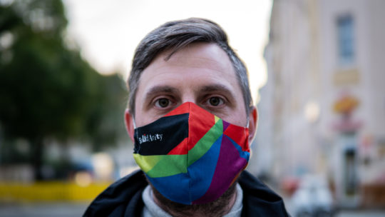 Junger Mann von vorne mit einer bunten Maske mit dem Aufdruck "Solidarity"