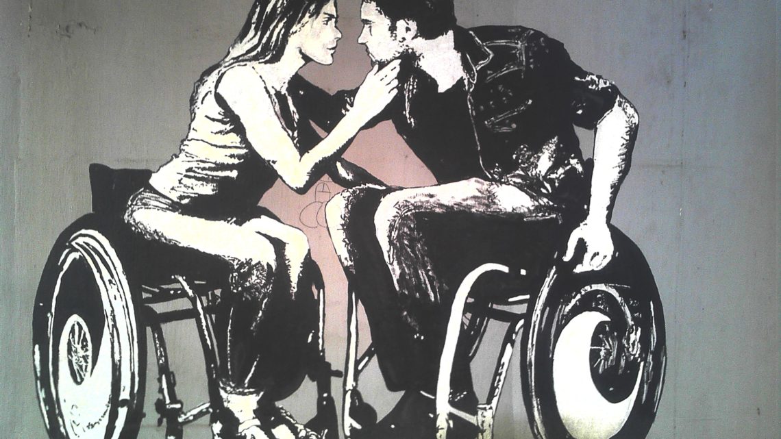 Zu sehen sind eine Rollstuhlfahrerin und ein Rollstuhlfahrer die sich liebevoll einander zugewendet haben. Das Motiv ist ein Graffito.