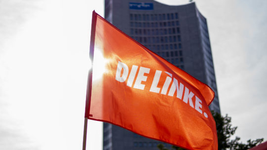 Zu sehen ist eine wehende Fahne von DIE LINKE vor dem Uniriesen in Leipzig