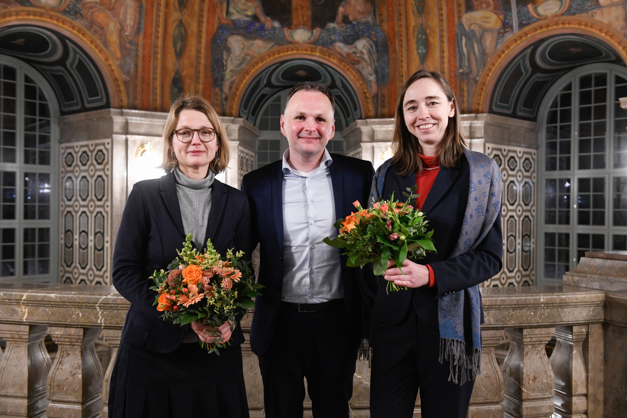 Annekatrin Klepsch und Kris Kaufmann mit Blumensträußen im Dresdner Rathaus, in der Mitte André Schollbach