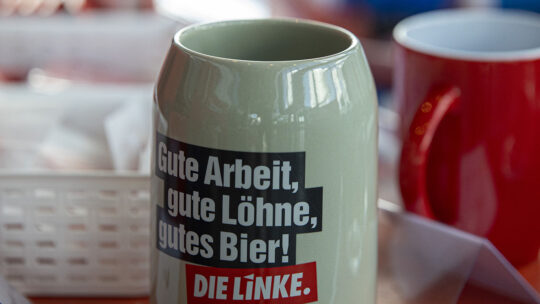 Foto von Bierkrug mit Aufschrift "Gute Arbeit, gute Löhne, gutes Bier" und Logo DIE LINKE